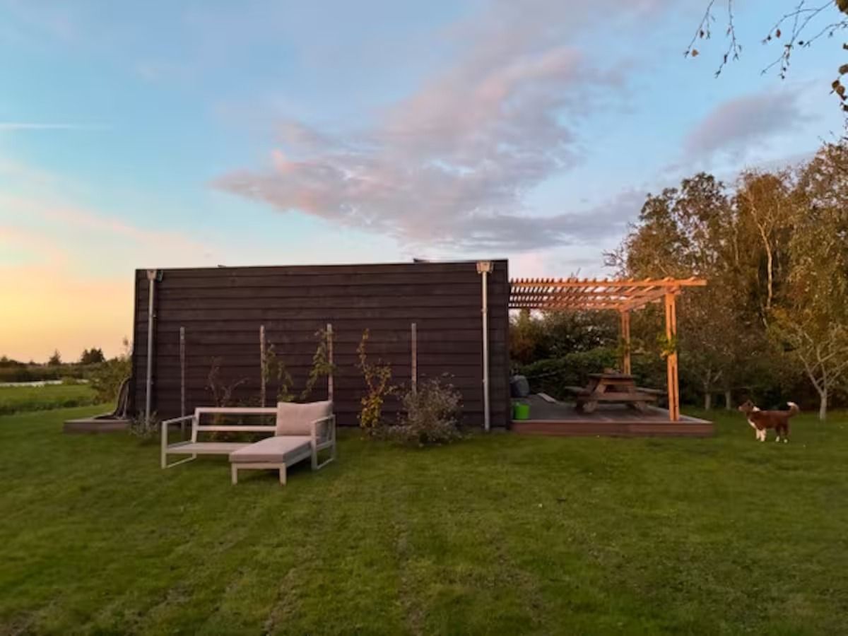 Het huis in avondlicht, met ligbedden op het gras
